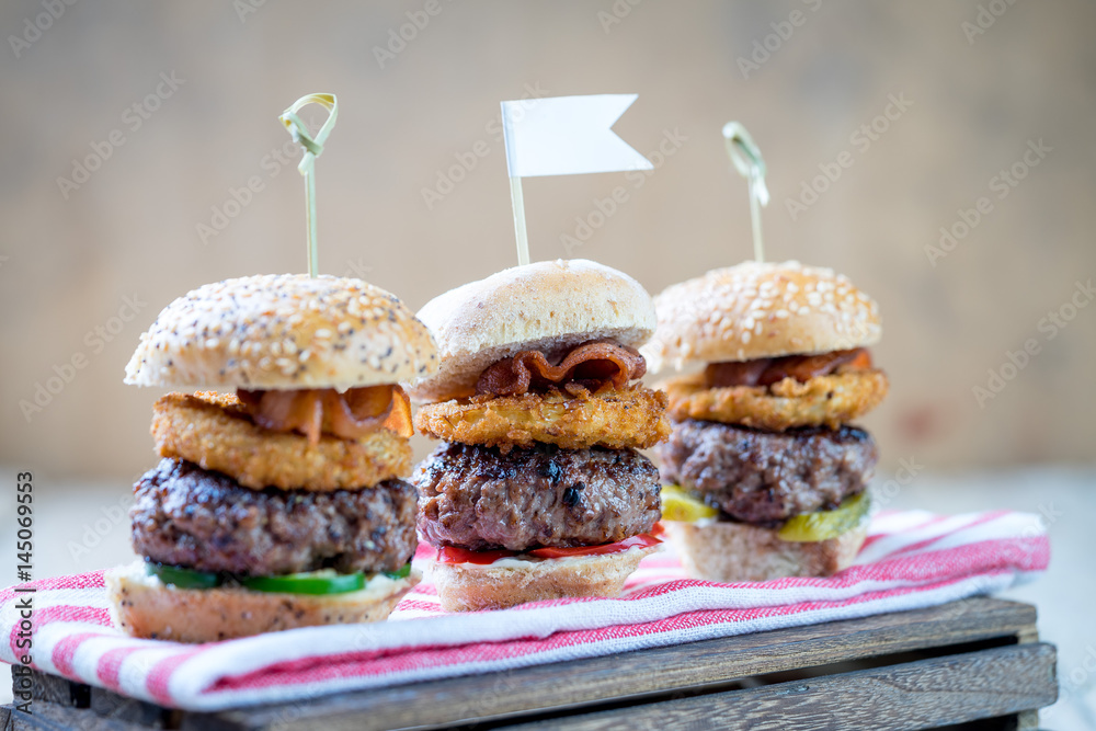 Small beef sliders grilled burgers onion rings little buns bacon served as appetisers for sharing