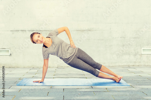 woman making yoga in side plank pose on mat