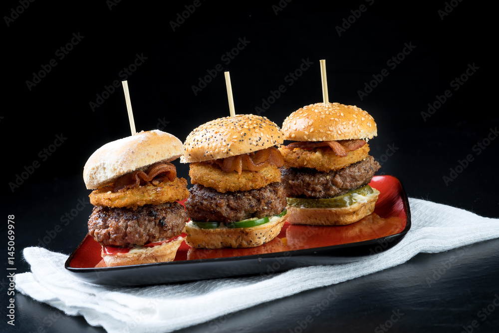 Small beef sliders grilled burgers onion rings little buns bacon served as appetisers for sharing
