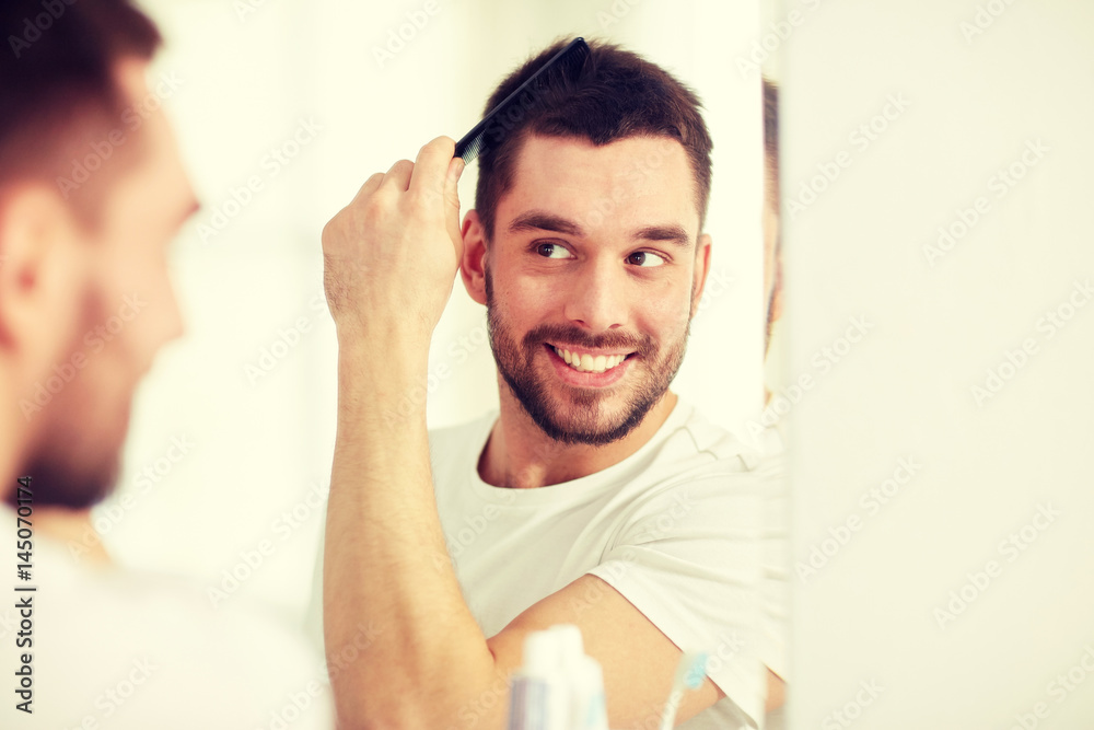 happy man brushing hair with comb at bathroom happy man brushing hair with comb at bathroom