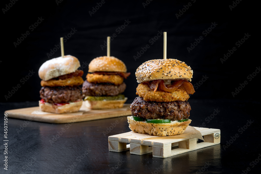 Small beef sliders grilled burgers onion rings little buns bacon served as appetisers for sharing