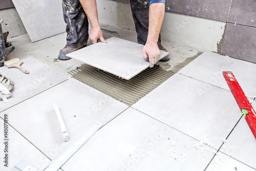 Tiling Floor & Wall. The tiler builder arranges the bathroom ceramics. Laying tiles on the floor
