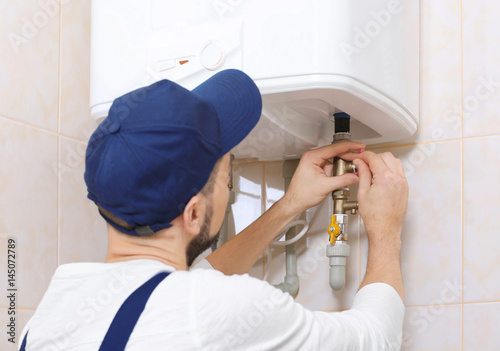 Schilderij op canvas Plumber installing water heater in bathroom