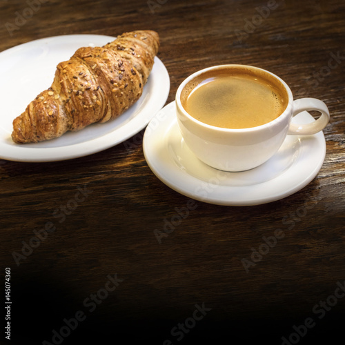 Fototapeta Naklejka Na Ścianę i Meble -  Cup of dark coffee with cereal croissant