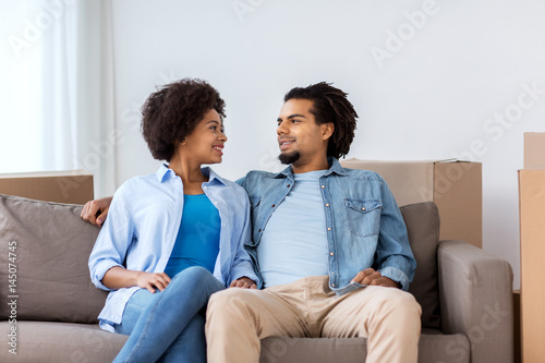 happy couple sitting on sofa and talking at home