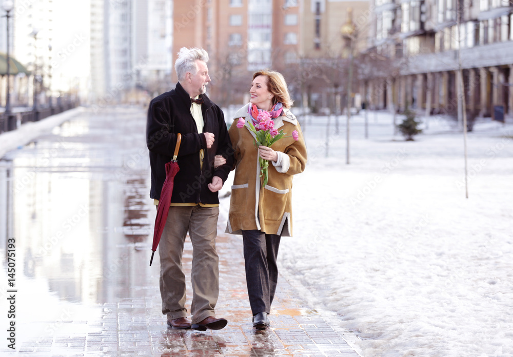 Happy senior couple with bouquet of flowers  on a walk