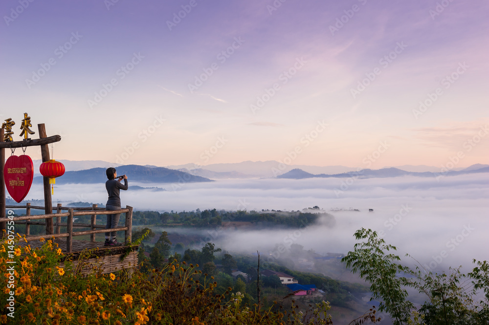 Obraz premium Tourist with Sunrise and sea of clouds over Pai District Mae Hong Son, THAILAND. View from Yun Lai Viewpoint is located about 5 km to the West of Pai town centre above the Chinese Village.