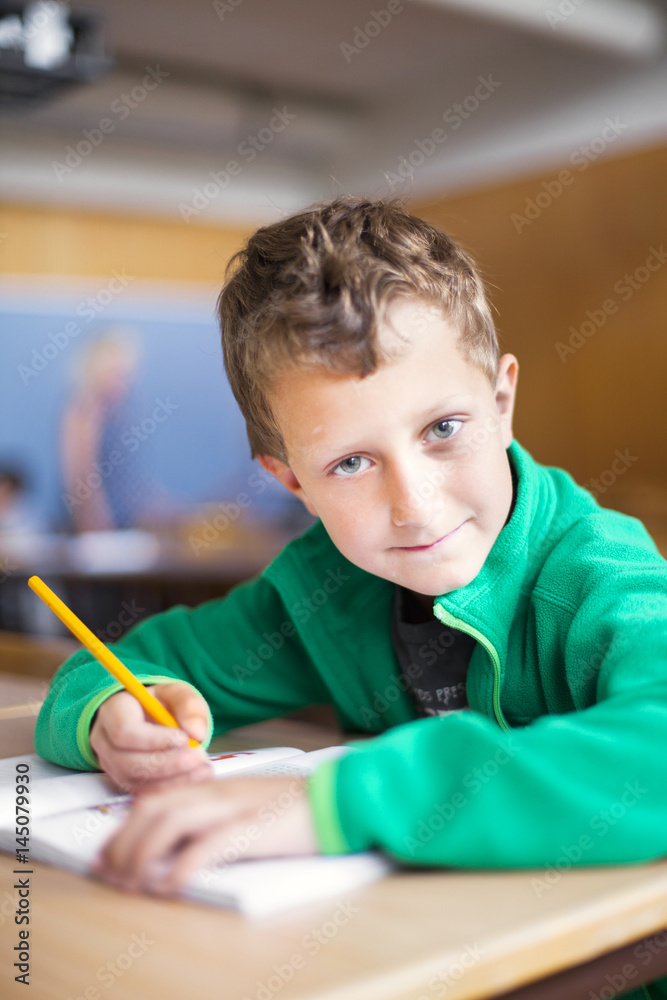 Portrait of confident schoolboy sitting at desk Portrait of confident schoolboy sitting at desk