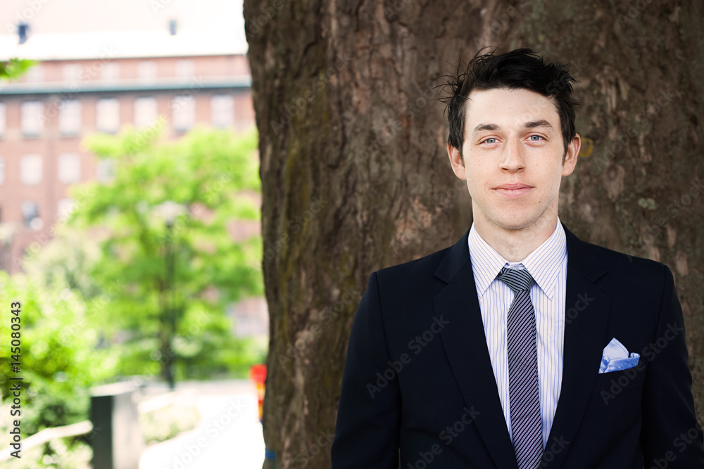 Portrait of confident businessman standing against tree trunk Portrait of confident businessman standing against tree trunk