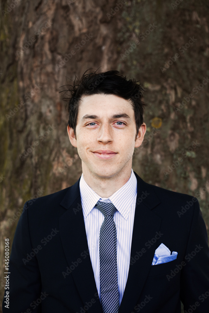 Portrait of smiling businessman standing against tree trunk Portrait of smiling businessman standing against tree trunk
