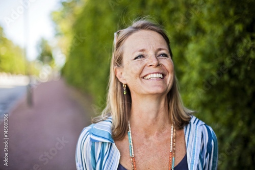 Beautiful young woman smiling on sidewalk photo