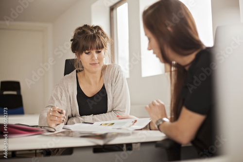 Businesswomen discussing about magazine during meeting in creative office