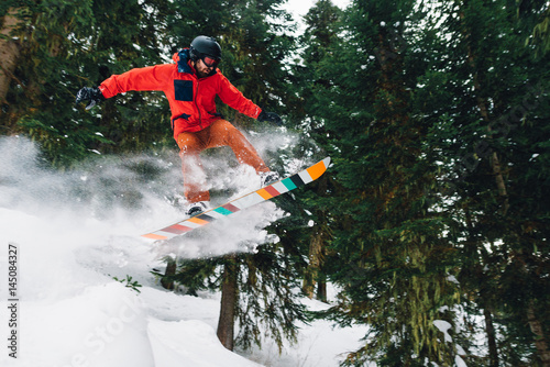 snowboarder with special equipment is riding and jumping very fast in the mountain forest photo