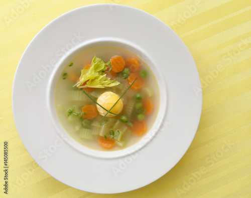 Vegetable spring soup with carrot, peas, celery and egg. Top view.