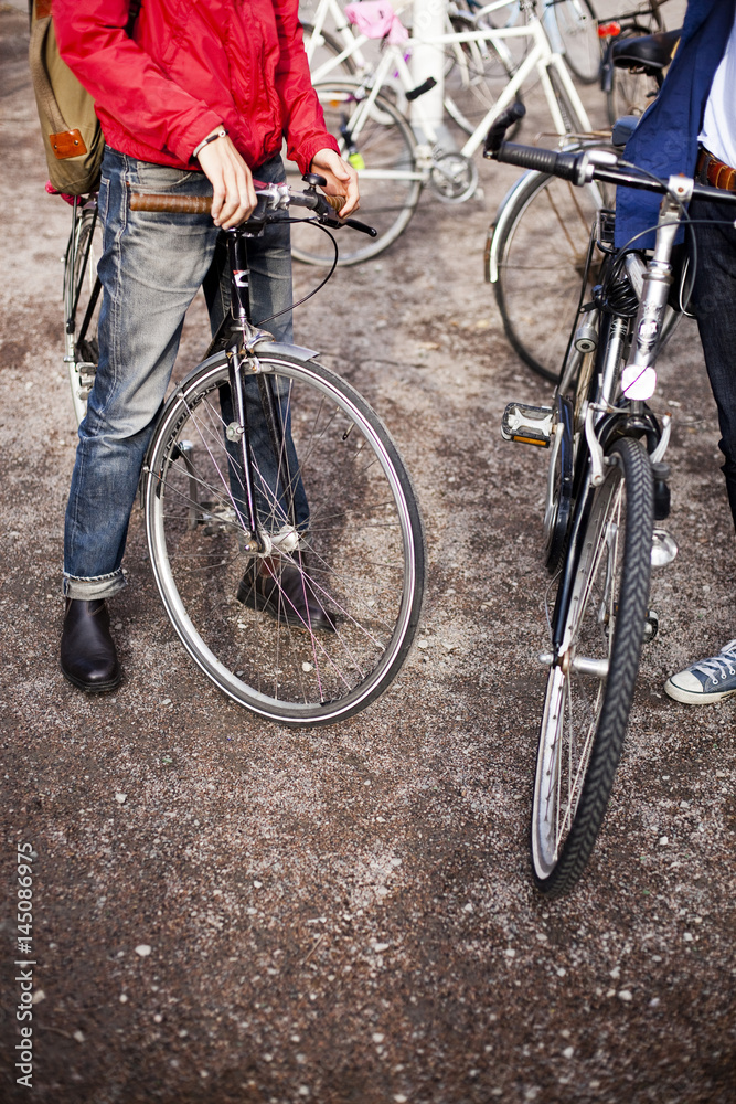 Low section of male friends standing with bicycles in campus Low section of male friends standing with bicycles in campus