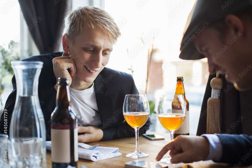 Two men looking at smartphone at restaurant table Two men looking at smartphone at restaurant table