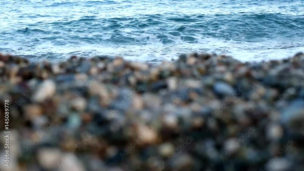 Closeup of blurred stony beach surface at blue sea waves background. Real time full hd video footage. Closeup of blurred stony beach surface at blue sea waves background. Real time full hd video footage.