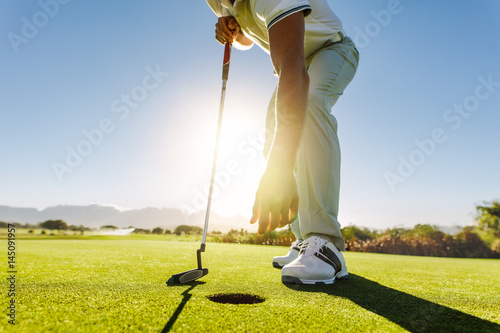 Golfer picking the ball from hole after put