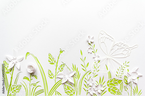 Summer flowering meadow. White flowers carved from paper on a white background with green leaves © EkaterinaVladimirova