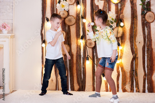 A little boy and girl are playing led lamps. They hold the bulbs in their hands.