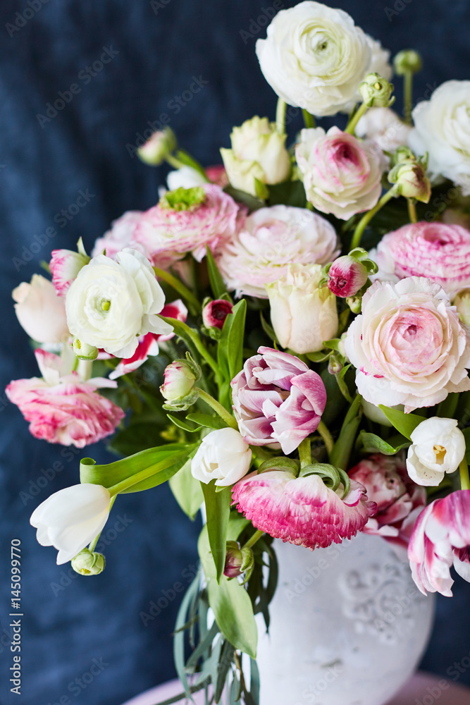 Flower arrangement with tulips and ranunculus on a white wooden floor. Spring flower 