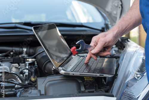 Mechanic using laptop for checking car engine