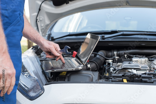 Mechanic using laptop for checking car engine © thodonal