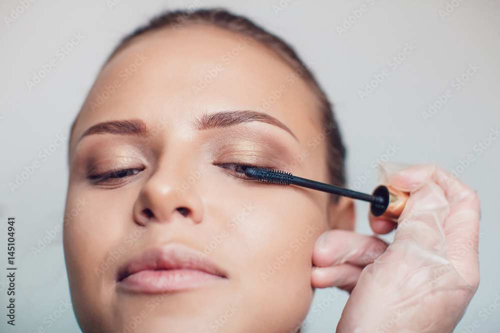 Professional make-up artist makes eye makeup of model. Beauty and fashion concept. Close up.