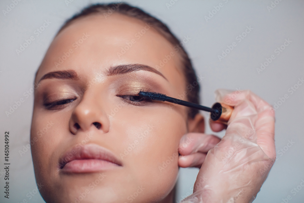 Professional make-up artist makes eye makeup of model. Beauty and fashion concept. Close up.