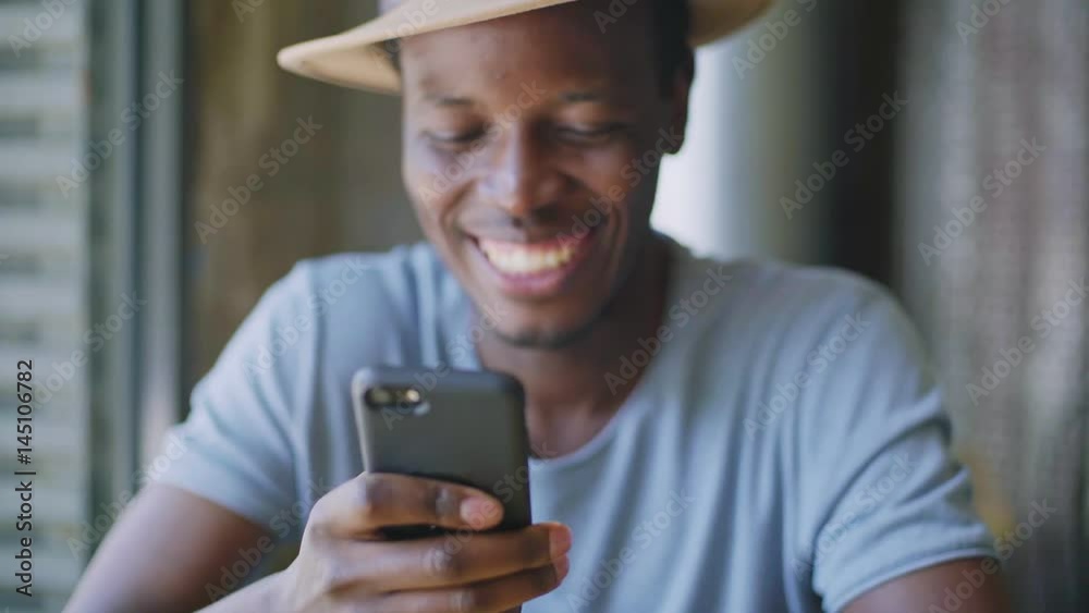 Hand held unfocused shot of a handsome black man laugh at a hillarious joke he received on a messaging application from a group chat with his friends.