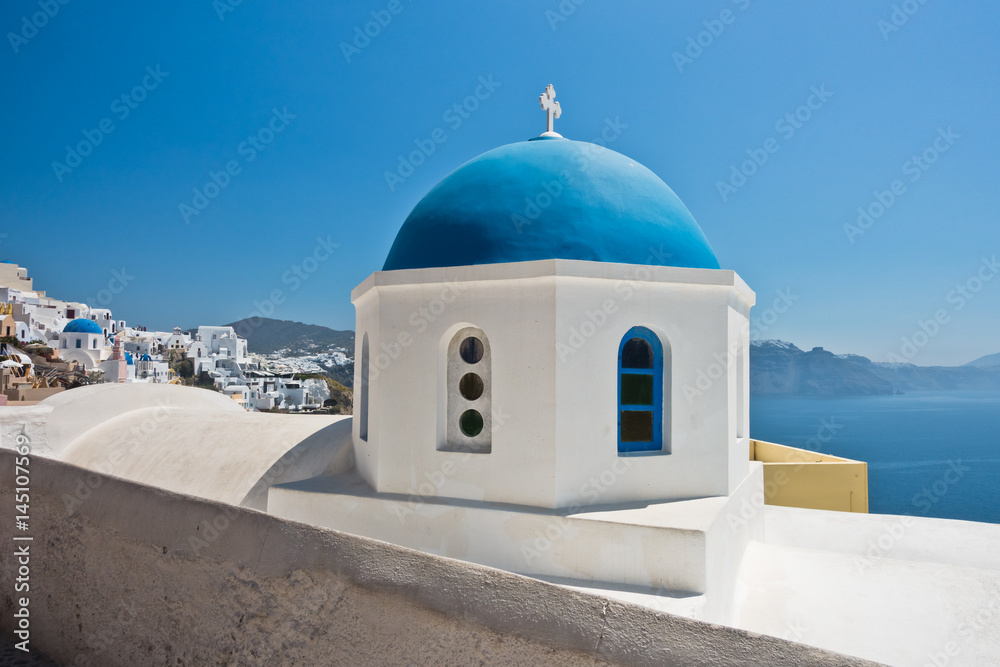 Blue dome of a white church with Caldera cliff in a background, Oia village, Santorini island, Greece
