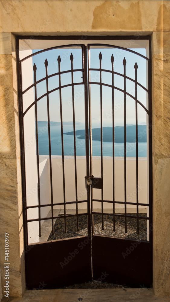 Gate with a view at blue sea and volcano, Imerovigli village, Santorini island, Greece Gate with a view at blue sea and volcano, Imerovigli village, Santorini island, Greece