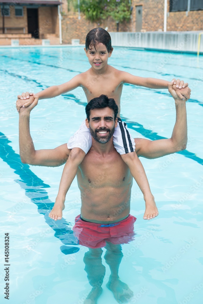 Father carrying son on shoulder in pool