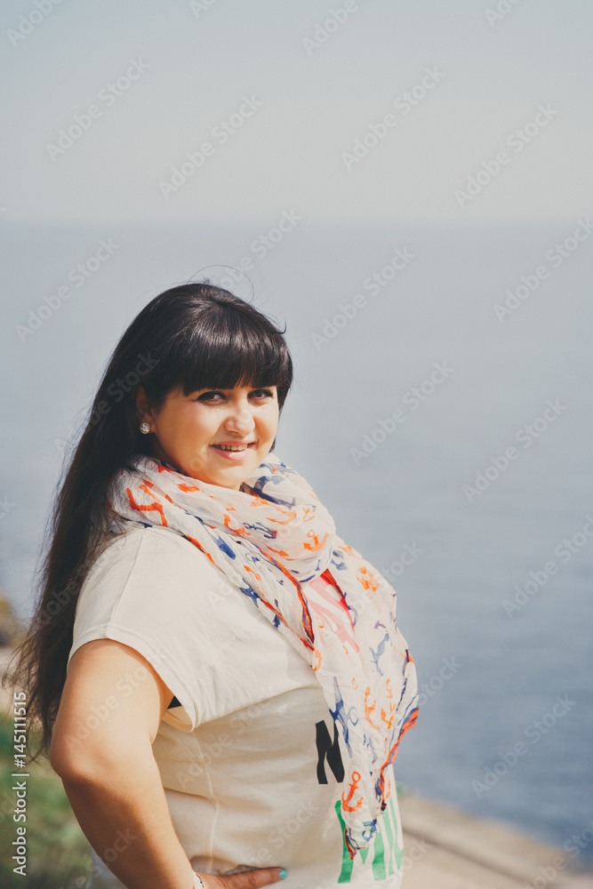 Happy smiling beautiful overweight young woman in white T-shirt and scarf with anchor outdoors near to the sea. Confident fat young woman. Xxl woman, plus size woman on nature. Happy smiling beautiful overweight young woman in white T-shirt and scarf with anchor outdoors near to the sea. Confident fat young woman. Xxl woman, plus size woman on nature.