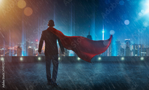 Businessman in a suit and cape hero facing a storm,victory concept. cityscape background , night scene . photo