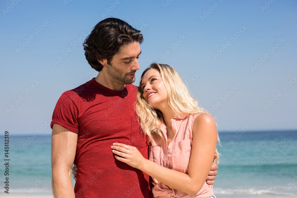 Couple with arm around standing on shore at beach Couple with arm around standing on shore at beach