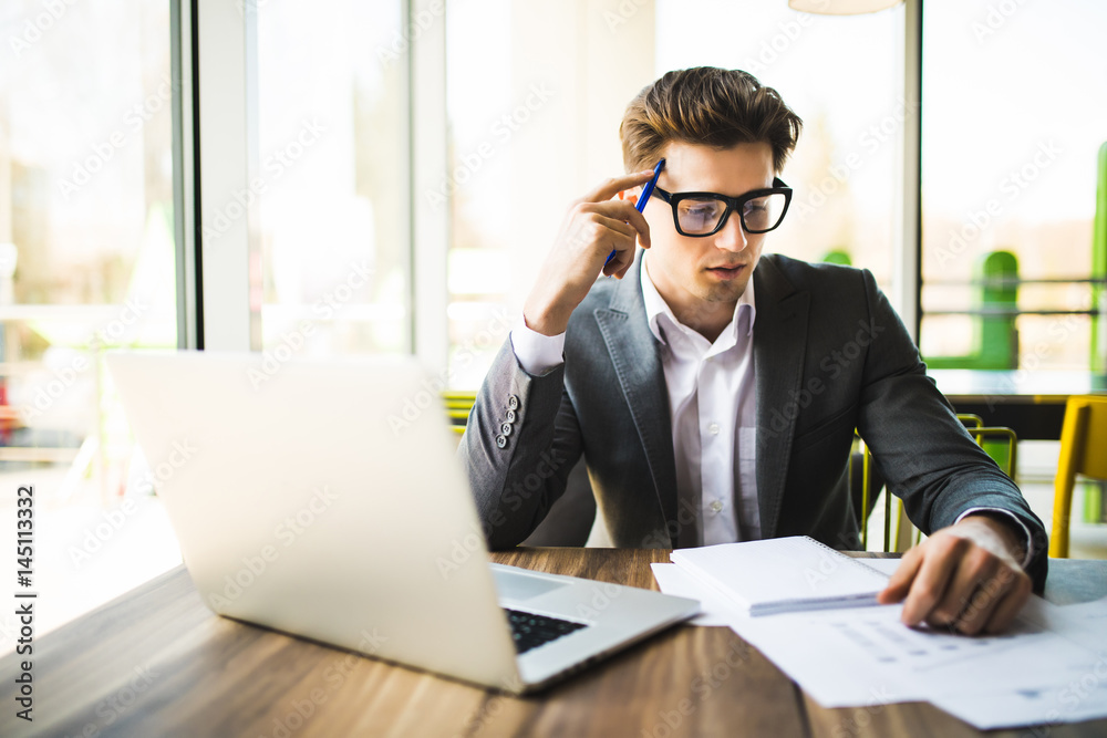 Fototapeta premium Happy man entering data from home on laptop an office work place