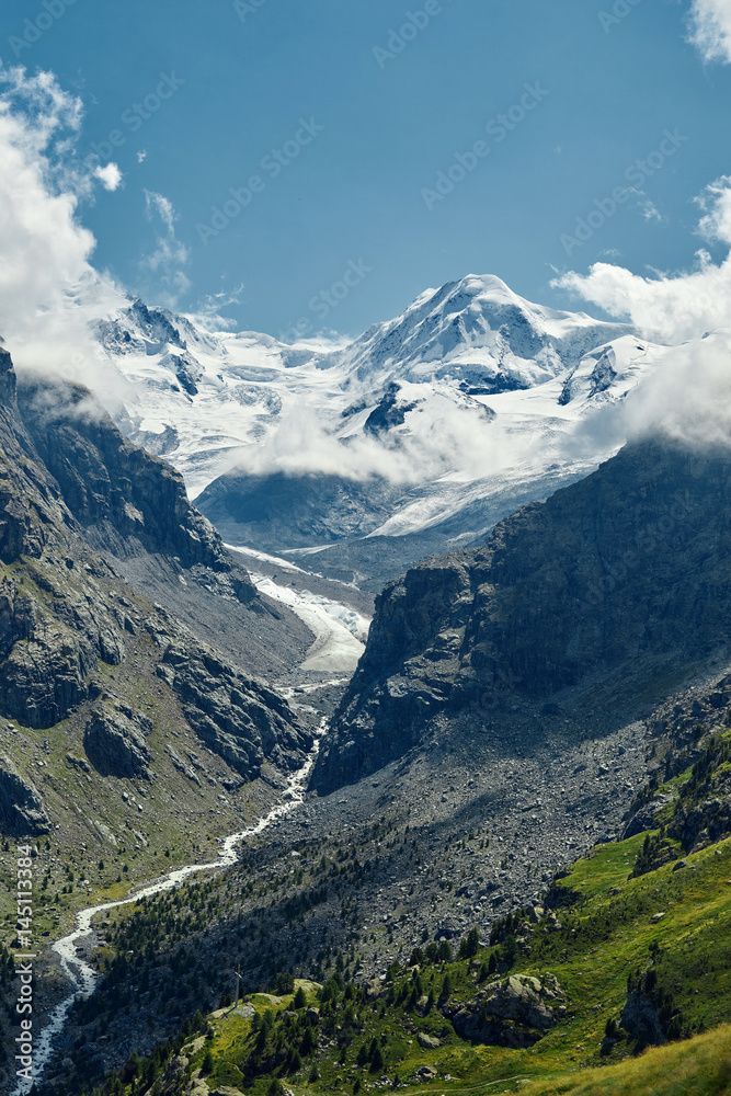 Snow capped alpine mountains. Trek near Matterhorn mount. View of the mountain and valley of a mountain river. Beautiful alpine landscape with a mountain path, Swiss Alps, Europe