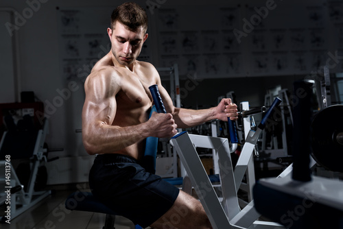 Young muscular man with a naked torso one trains in the gym