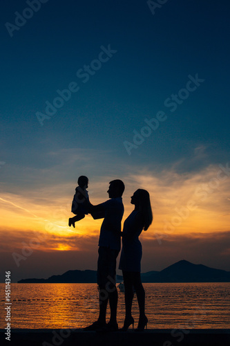 Silhouette of a family with children against the backdrop of the setting sun and sea in Montenegro.