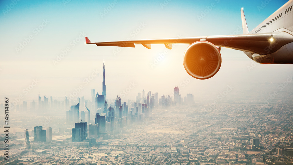 Naklejka premium Close-up komercyjnego samolotu lecącego nad nowoczesnym miastem