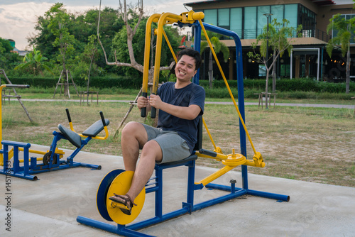 Happy young Man on machine exercising in a Park.