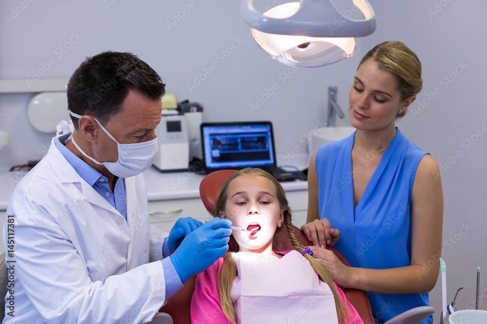 Dentist examining a young patient with tools Dentist examining a young patient with tools