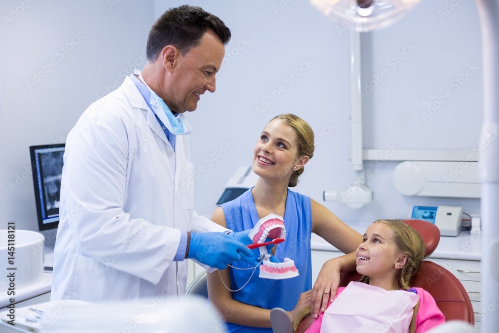 Obraz premium Dentist showing young patient how to brush teeth