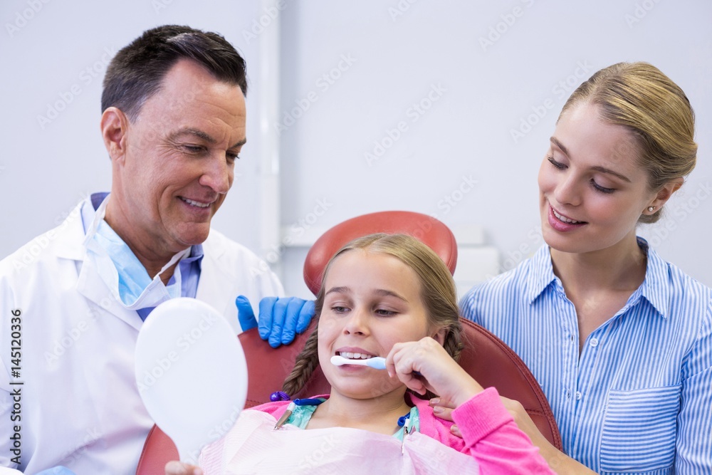 Dentist assisting young patient while brushing teeth Dentist assisting young patient while brushing teeth