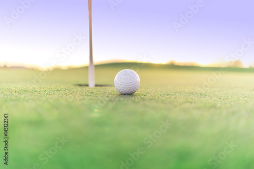 Golf ball close to hole on green, close up super wide angle. Lots of opportunity for copy text.