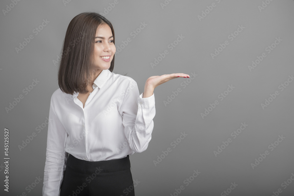 Beautiful Business Woman presenting something on grey background Beautiful Business Woman presenting something on grey background