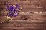 A bouquet of wildflowers related twine on brown wooden boards . Texture , background