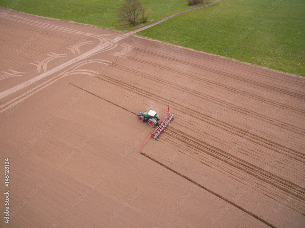 Fototapeta tractor - aerial view of a tractor at work cultivating a field in spring