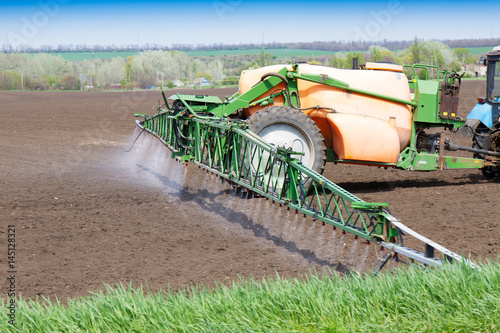 The tractor fertilizes the field, the genetically modified products